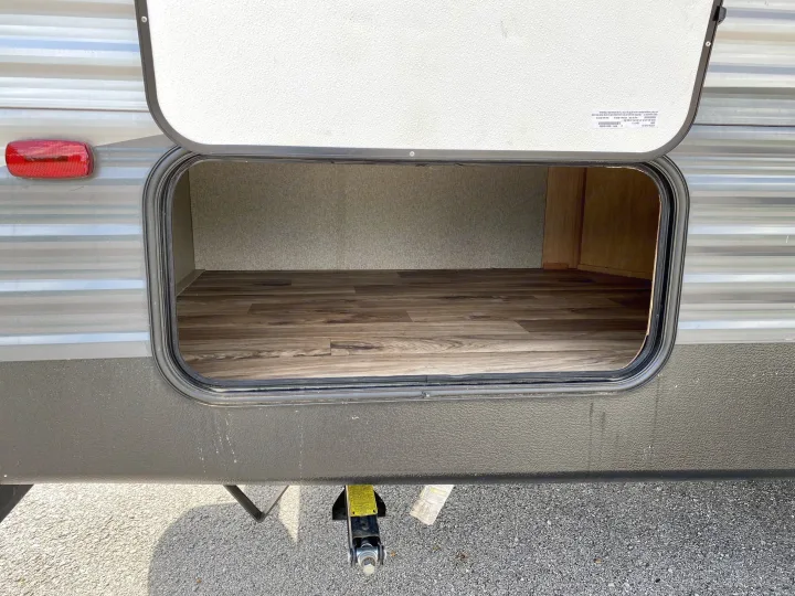 Open RV rental exterior storage bay with wood-look flooring, ready for your gear.. Keystone Springdale 2018