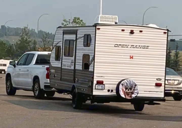 White pickup towing an Open Range travel trailer RV rental. Notice the cat-faced spare tire cover. Ready for adventure!. Highland Ridge RV Open Range 2021