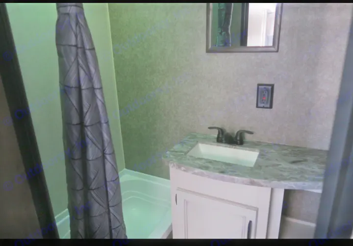RV rental interior bathroom: Dark shower curtain next to a vanity with a white sink, black faucet, and mirror.. Highland Ridge RV Open Range 2021