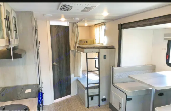 Spacious RV rental interior featuring a kitchen, bunk beds, and dining area. Perfect for family adventures!. Forest River All American Sport 2021