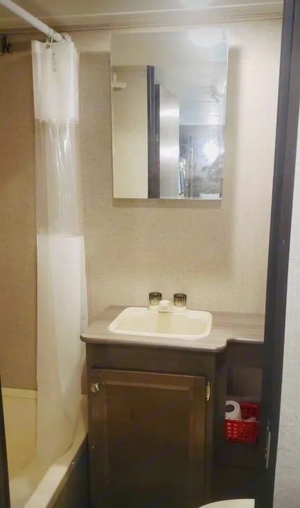 Compact RV rental bathroom with shower, sink, vanity, and mirror. Essentials like toilet paper are visible.. Dutchmen Other 2018
