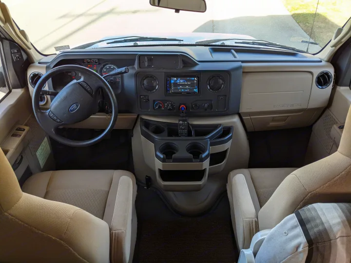 This Ford RV rental interior showcases the dashboard, steering wheel, and spacious front cabin seats, ready for adventure.. Winnebago Minnie Winnie 2016