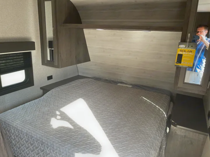 Explore this RV rental's bedroom: Features a comfy bed, overhead cabinets, and a window, reflecting solar power readiness.. Jayco Baja 2021