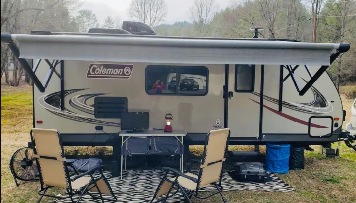 Enjoy a comfortable outdoor setup with this Coleman RV rental, complete with an awning, chairs, and fan for camping.. Dutchmen Other 2018