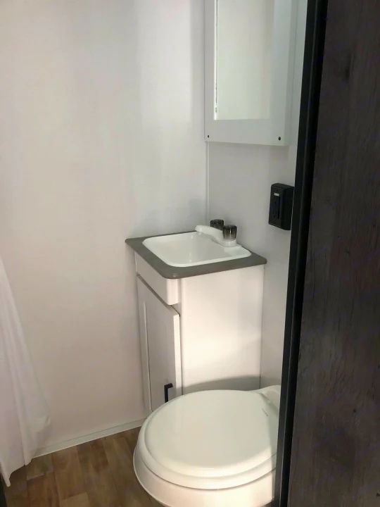 Compact RV rental bathroom: functional design with toilet, sink, mirror, and shower curtain. Ideal for mobile living.. Keystone RV Hideout 2021