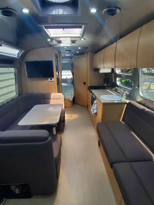 Long shot of a bright RV rental interior: lounge, kitchen, and bedroom visible. Perfect for comfortable travel adventures.. Airstream Flying Cloud 2018