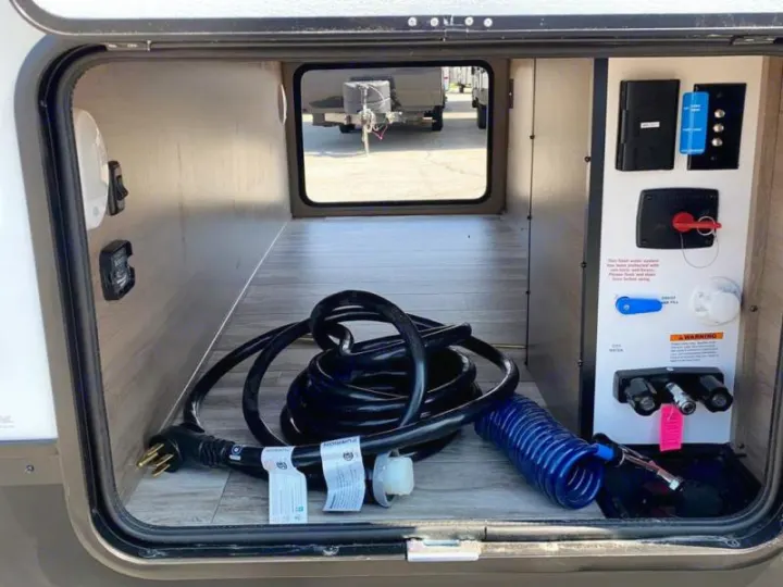 RV rental: Interior view of an RV's external utility compartment, showing power cord, water hookups, & control panel.. Grand Design Other 2021