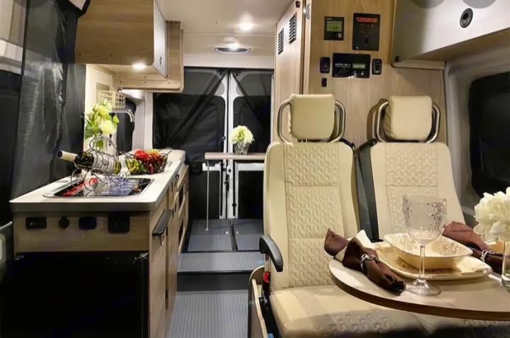This inviting RV rental interior features a compact kitchen, comfortable dining area with swivel seats, and controls, perfect for travel adventures.. Winnebago Solis 2021