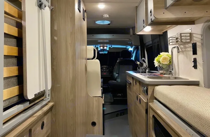 Compact RV rental interior featuring a functional kitchen, convertible bed, and comfortable living space. Perfect for travel.. Winnebago Solis 2021