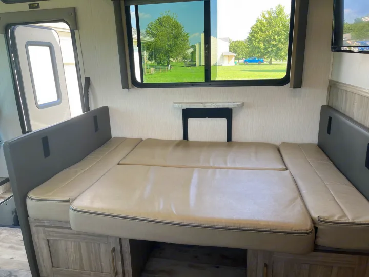 Spacious RV rental dinette transformed into a comfy bed, offering versatile living with a view.. Coachmen Pursuit 2021