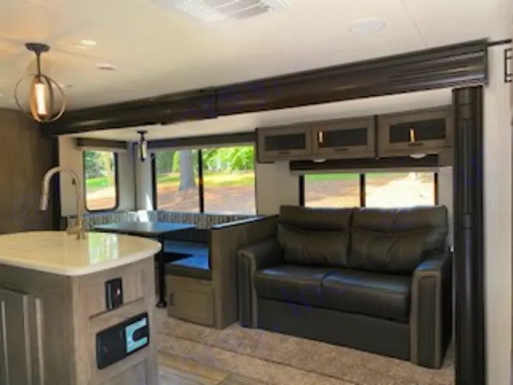 RV rental interior: A bright, inviting living area with a kitchen island, dining booth, and comfortable sofa.. Heartland RVs North Trail 2020
