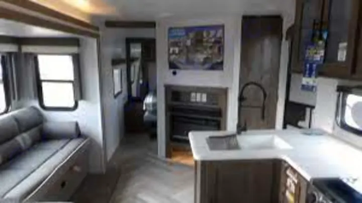 Explore this modern RV rental interior featuring a comfy sofa, kitchen, and electric fireplace.. Forest River Salem 2023
