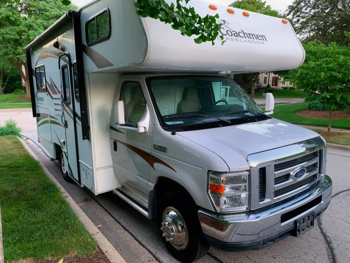 White Coachmen Freelander RV rental, built on a Ford E350 chassis, is parked on a residential street.. Coachman Ford E350 2013