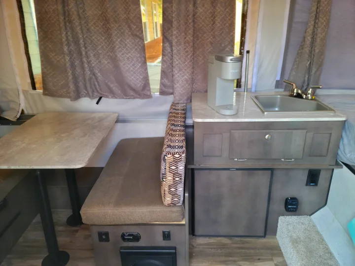 RV rental: Inside a pop-up camper featuring a dining table, bench, sink, Keurig coffee maker, and Dometic refrigerator.. Forest River Flagstaff 2021