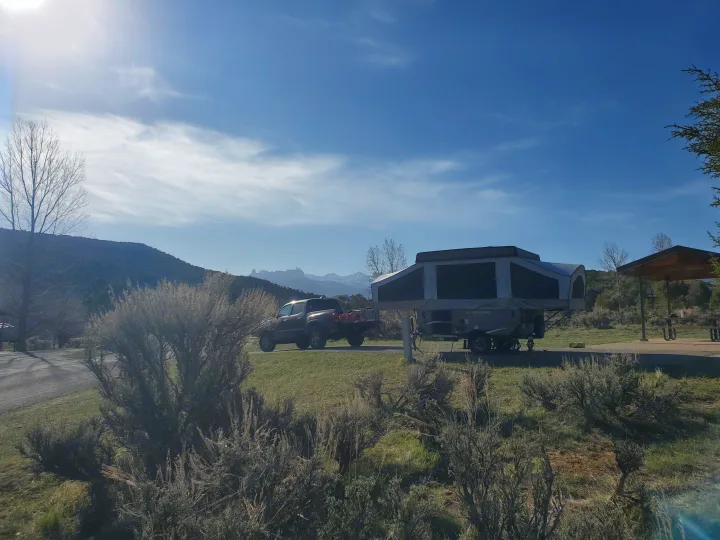 Sunny campsite with pickup truck & RV rental amidst mountains & trees.. Forest River Flagstaff 2021
