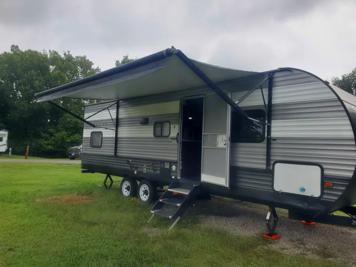 An RV rental travel trailer is parked at a campsite with its awning deployed, ready for adventure.. Forest River Salem 2019