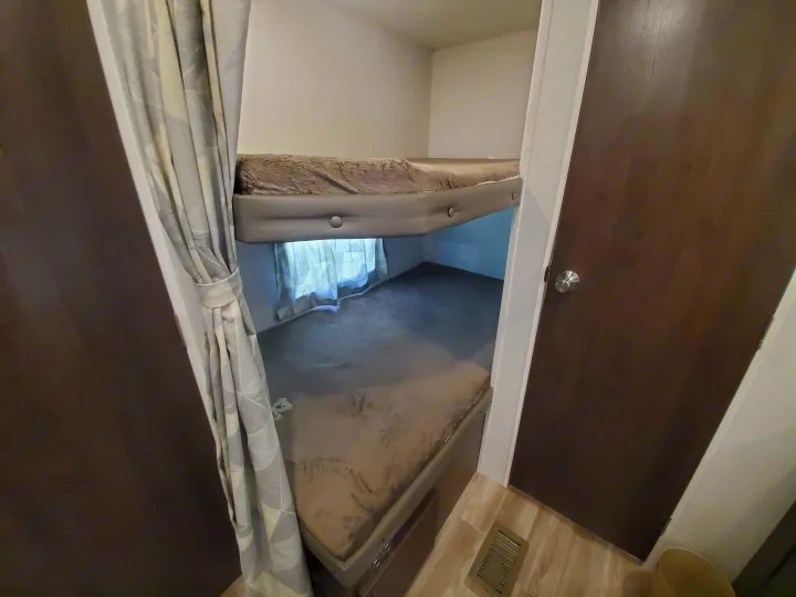 Dual bunk beds with plush mattresses and privacy curtains inside an RV rental, providing cozy sleeping space.. Forest River Salem 2019