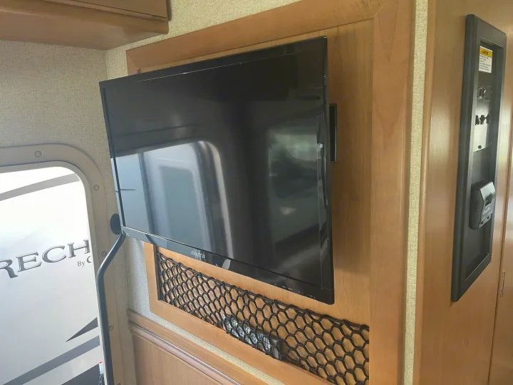 RV rental interior: Axxera TV, control panel, and mesh storage net in a modern camper, offering comfort.. Thor Four Winds 2021