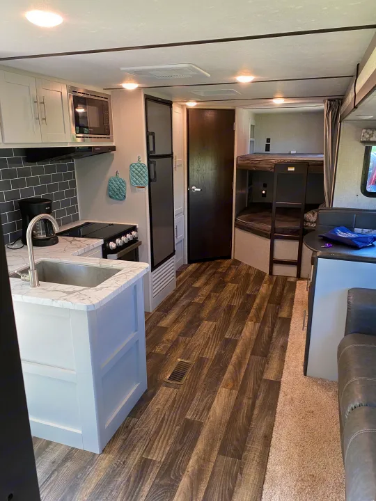 Modern RV rental interior: kitchen, bunk beds, dinette, wood floors. Great for road trips!. Keystone Bullet 2020