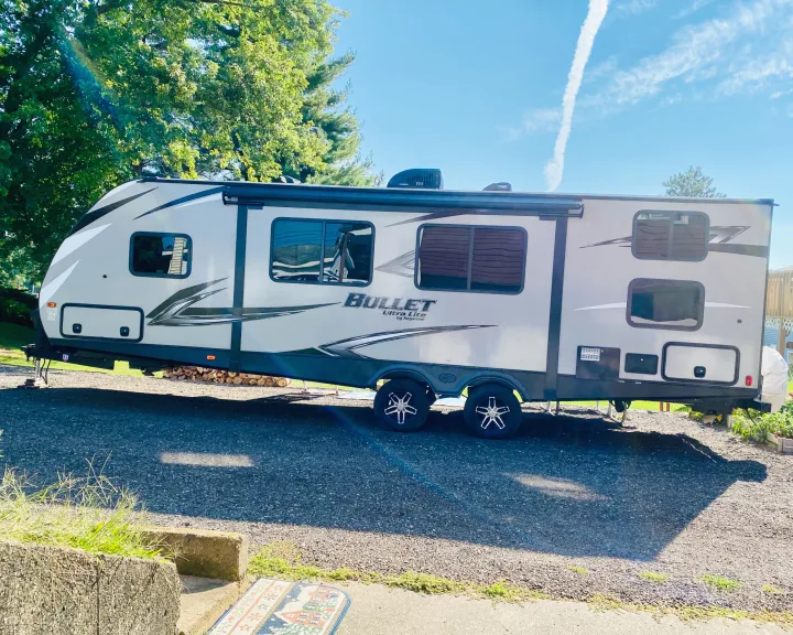 Sleek gray travel trailer parked on gravel under sunny skies, ideal for an RV rental adventure.. Keystone Bullet 2020