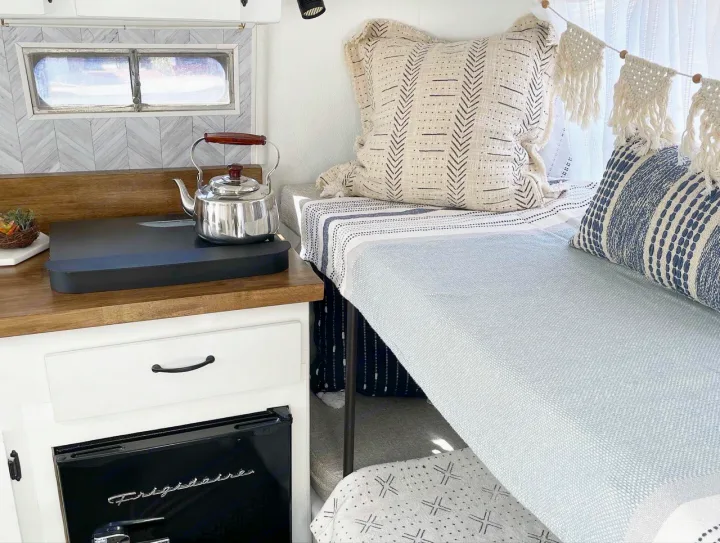 Cozy RV rental interior featuring a compact kitchen with kettle, Frigidaire fridge, and a stylish sleeping nook.. Scamp 13' 1979