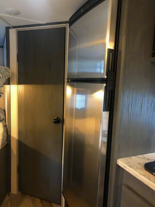 RV rental: modern stainless steel refrigerator and interior door within a compact living space.. Dutchman Aspen Trail 2022
