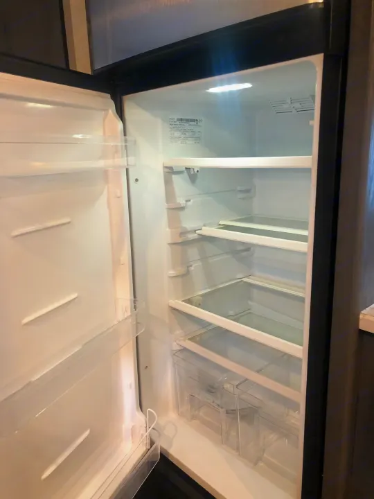 A clean, empty RV rental refrigerator, ready for your trip. Features clear shelves and door storage.. Dutchman Aspen Trail 2022
