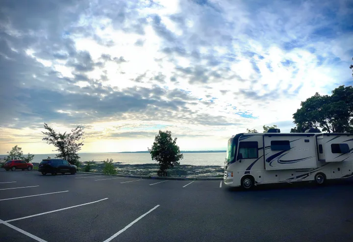 A spacious Jayco Alante RV rental, a Class A motorhome, parked by a scenic waterfront under cloudy skies.. Jayco Other 2021