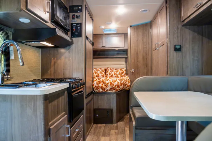 Spacious RV rental interior featuring a modern kitchen, cozy bed nook, and comfortable dinette. Perfect for your next adventure.. Winnebago Minnie Winnie 2021
