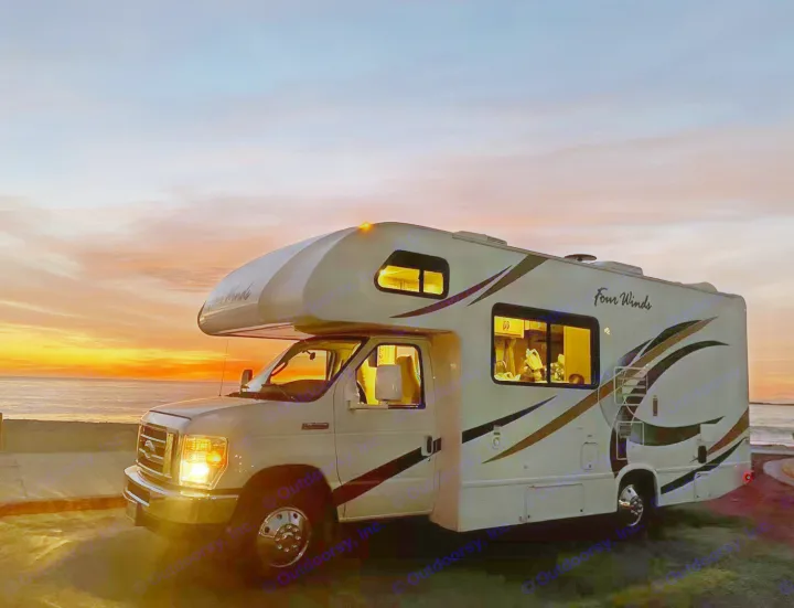 Scenic coastal escape with an rv rental. This Four Winds motorhome lights up at sunset by the tranquil ocean.. Thor Four Winds 2019