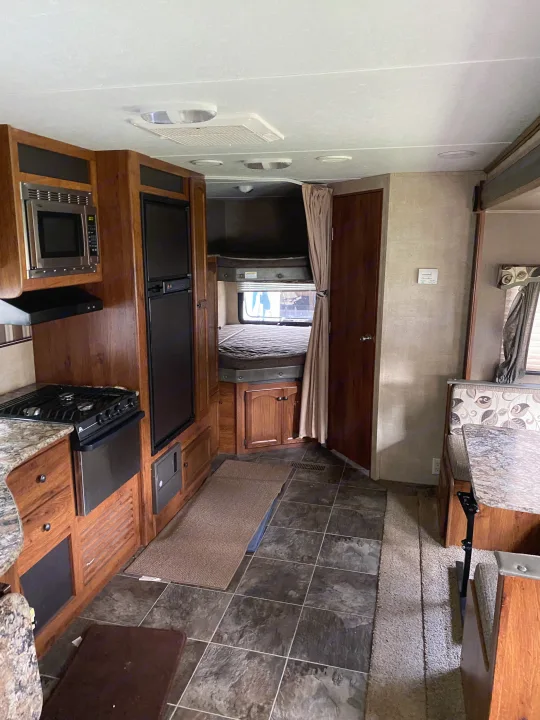 Spacious RV rental interior featuring a kitchen with appliances, bunk beds, and a dinette, offering comfortable travel accommodations.. Keystone Hideout 2014