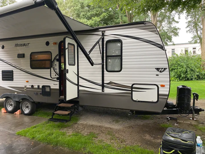 Experience an RV rental: This Keystone Hideout travel trailer is set up at a damp campsite with its awning extended.. Keystone Hideout 2014