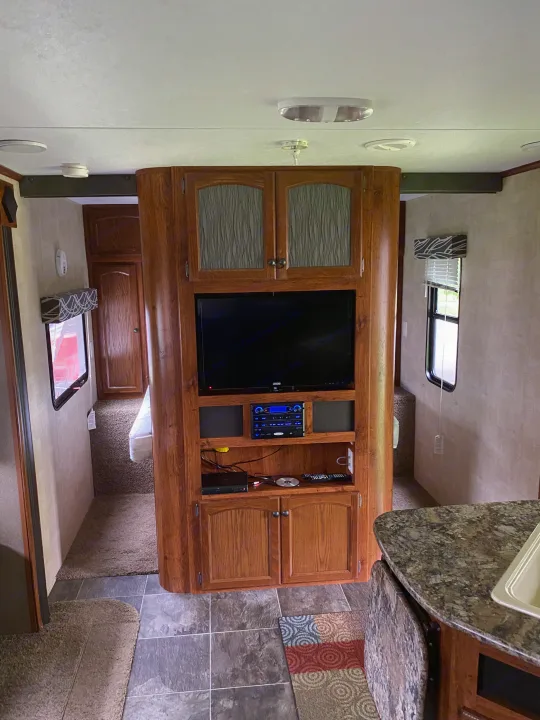Explore this well-appointed RV rental interior featuring a TV, stereo, kitchen counter, and comfortable sleeping area.. Keystone Hideout 2014
