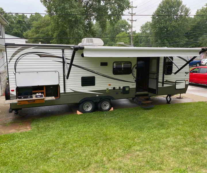 This RV rental, a travel trailer, features an outdoor kitchen and extended awning, set for comfortable use.. Keystone Hideout 2014
