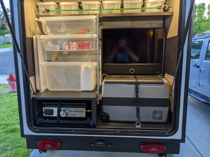 Organized RV rental rear compartment features an outdoor kitchen with a Blackstone griddle, portable cooler, and tiered storage bins.. Jayco Jay Feather Micro 12SRK 2021