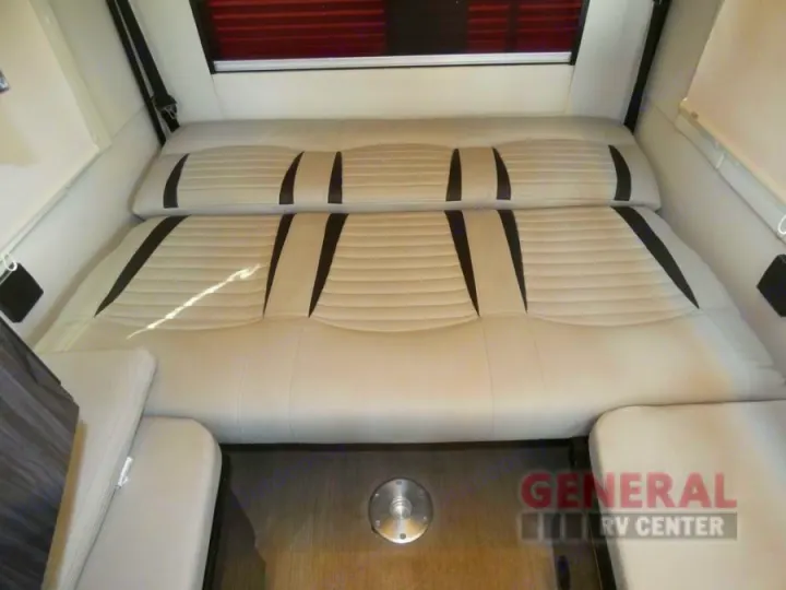 Comfortable RV rental interior with a convertible bed and seating area. Features cream cushions with black accents.. Winnebago Era 2021
