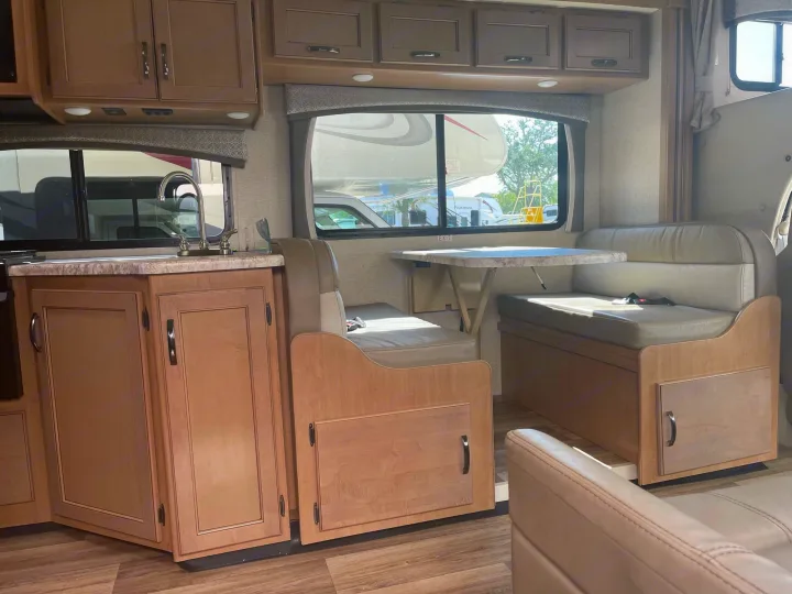 RV rental interior: a clean, functional space with kitchen, dinette seating, and overhead cabinets for travel comfort.. Thor Four Winds 2021