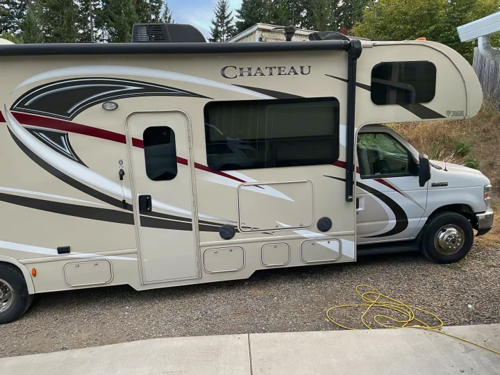 Side view of a beige and maroon Thor Chateau RV parked on gravel, ready for an rv rental adventure.. Thor Motor Coach Chateau 2017