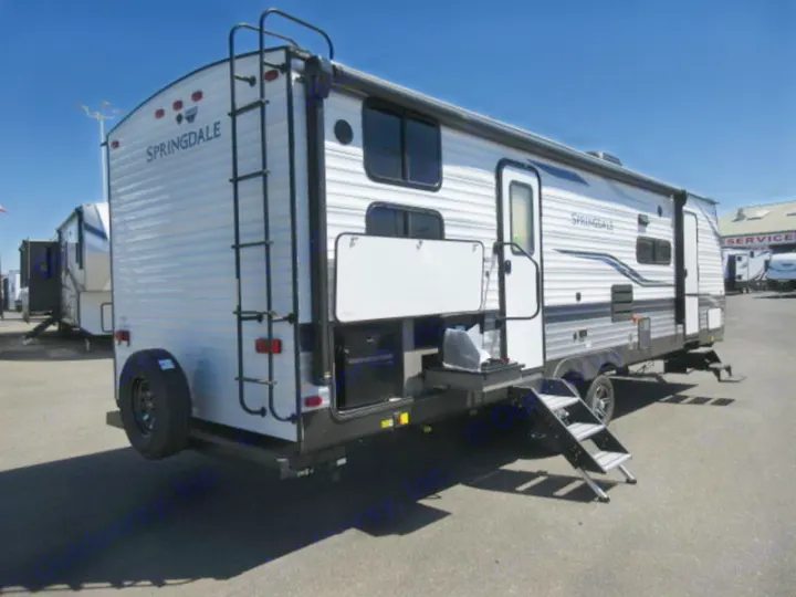 White Springdale travel trailer, ideal for an rv rental, showing its outdoor kitchen, rear ladder, and entry steps.. Keystone Springdale 2022