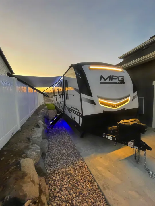 MPG Ultra-Lite RV with awning extended, lit up at dusk. Explore travel trailer RV rental options!. Other Other 2021