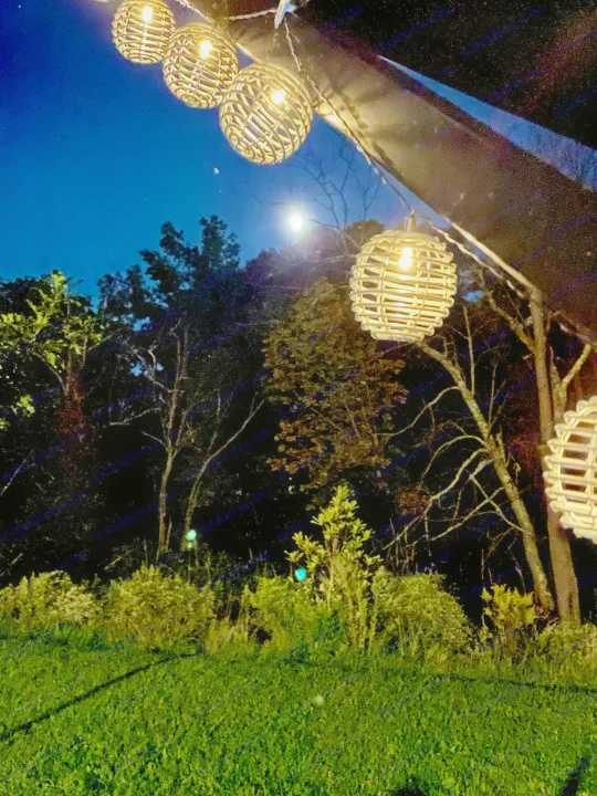 Experience cozy nights with an RV rental! String lights illuminate the moon, trees, and green grass creating a peaceful ambiance.. Forest River Independence Trail 2021