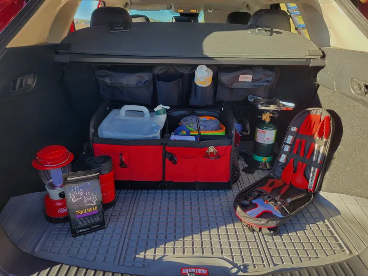 RV rental prep: Car trunk organized with camping gear, including stove, lantern, coffee, and cooking utensils for adventure.. Mazda Campervan 2018