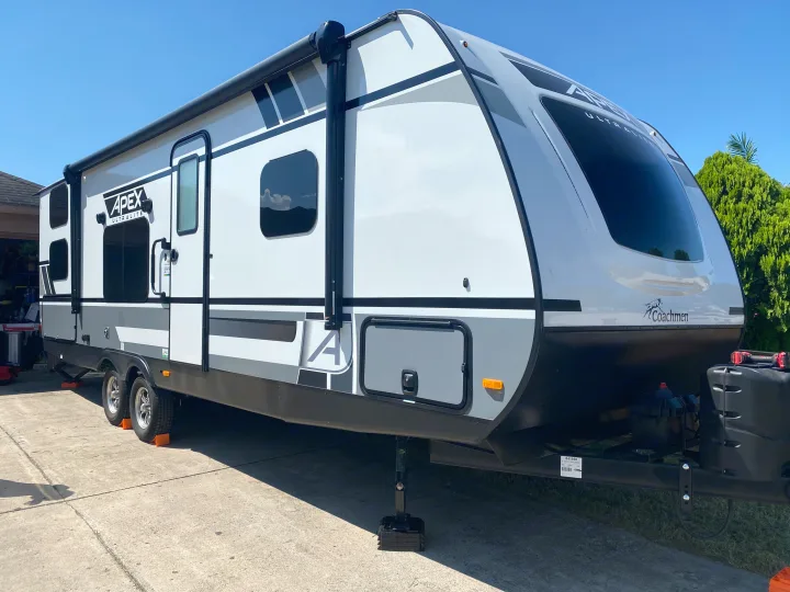 A parked Coachmen Apex Ultralite travel trailer, ideal for an RV rental. White & gray exterior on a sunny day.. Coachmen Other 2021