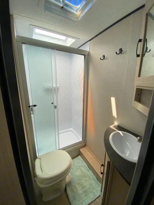 Inside an RV rental, a compact yet complete bathroom with a spacious shower, toilet, and vanity sink for your travels.. Coachmen Other 2021