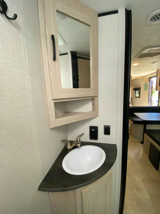Modern RV rental bathroom with compact sink, vanity, mirror, and storage, offering functional space.. Coachmen Other 2021