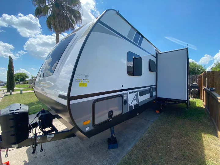 This RV rental travel trailer is parked on a sunny day, showcasing its extended slide-out for comfortable outdoor living.. Coachmen Other 2021