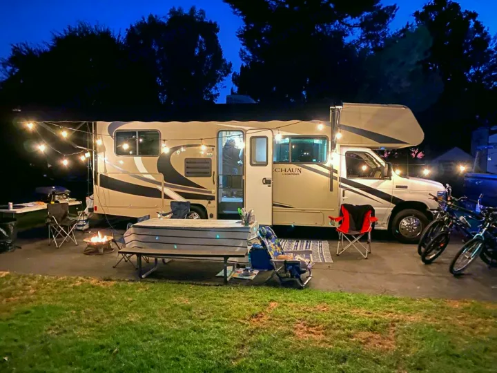 Enjoy a cozy night at this illuminated RV rental campsite, complete with string lights, fire pit, chairs, and bikes.. Coachmen Leprechaun 2021
