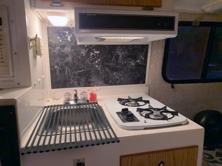 RV rental kitchen: Compact space featuring a two-burner stove, sink with drying rack, and overhead vent hood. Ideal for travel.. Casita 17' Spirit Deluxe 2010