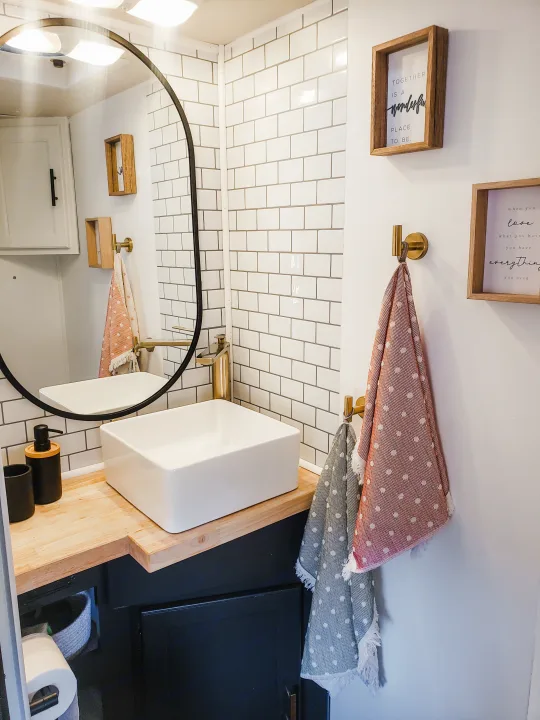 Bright RV rental bathroom with modern vessel sink, warm wood counter, subway tile, and inspiring decor.. Coachmen Freelander 2014