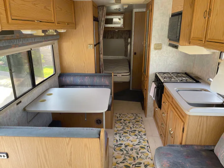 Full view of a well-equipped RV rental interior, showcasing the kitchen, dinette, and sleeping area.. Itasca Spirit 1995